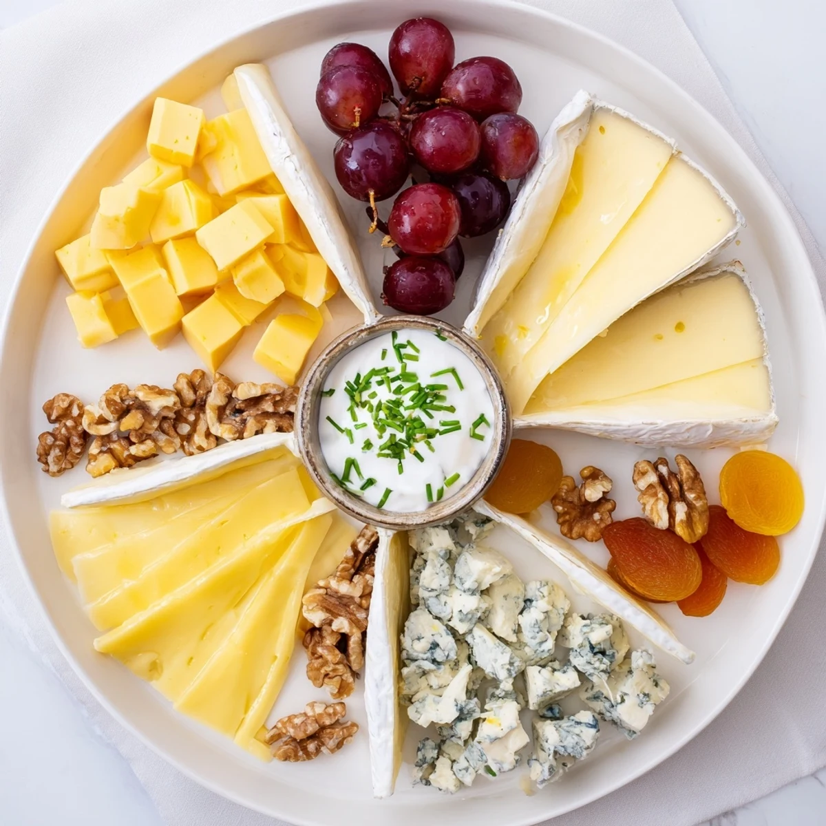 This The Celtic Cross Cheese Platter features four cheese sections artfully arranged with fruit and nuts.