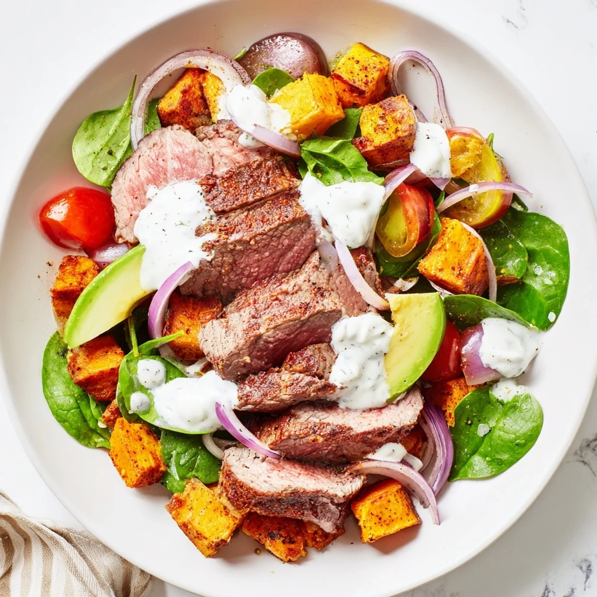This healthy beef avocado sweet potato bowl features colorful veggies, juicy beef, and tangy dressing.