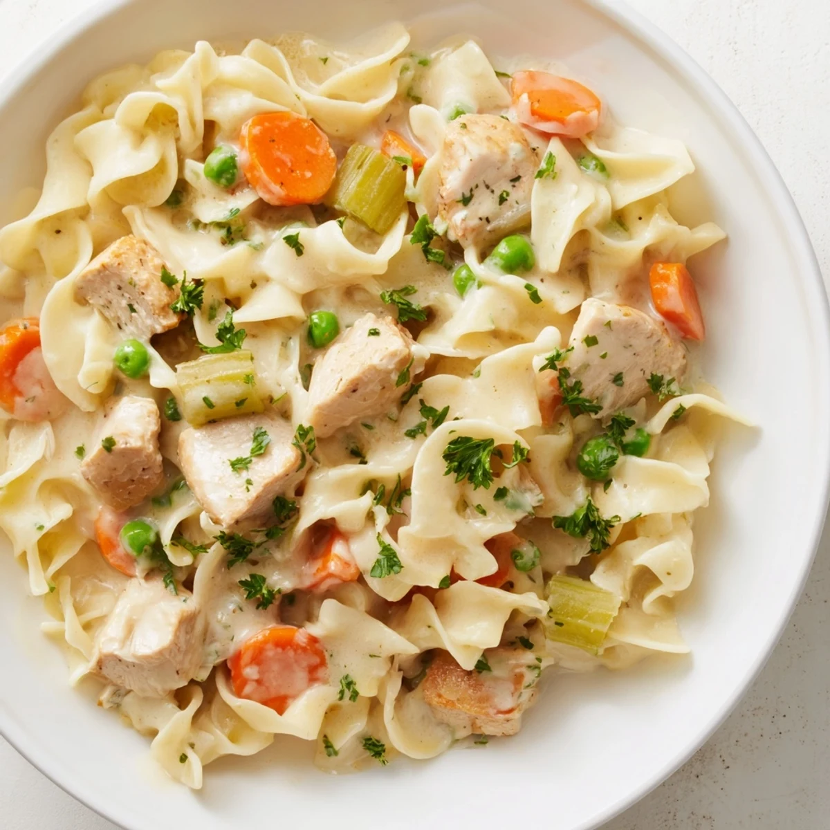 Steaming bowl of creamy chicken and egg noodles, perfect for a cozy, comforting dinner.