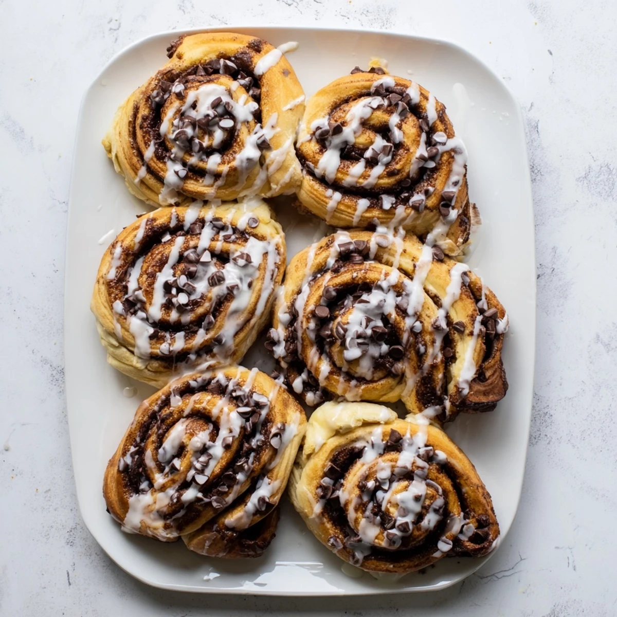 A close-up view of gooey Nutella Chocolate Chip Rolls reveals the rich, dark chocolate filling swirling through soft, pillowy dough and extra chocolate chips.