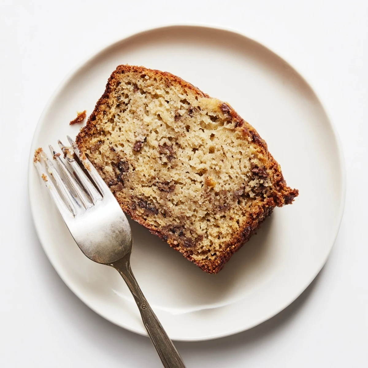 A freshly baked loaf of moist banana bread with chocolate chips, sliced to show a tender crumb and gooey pockets, served warm on a wooden board.