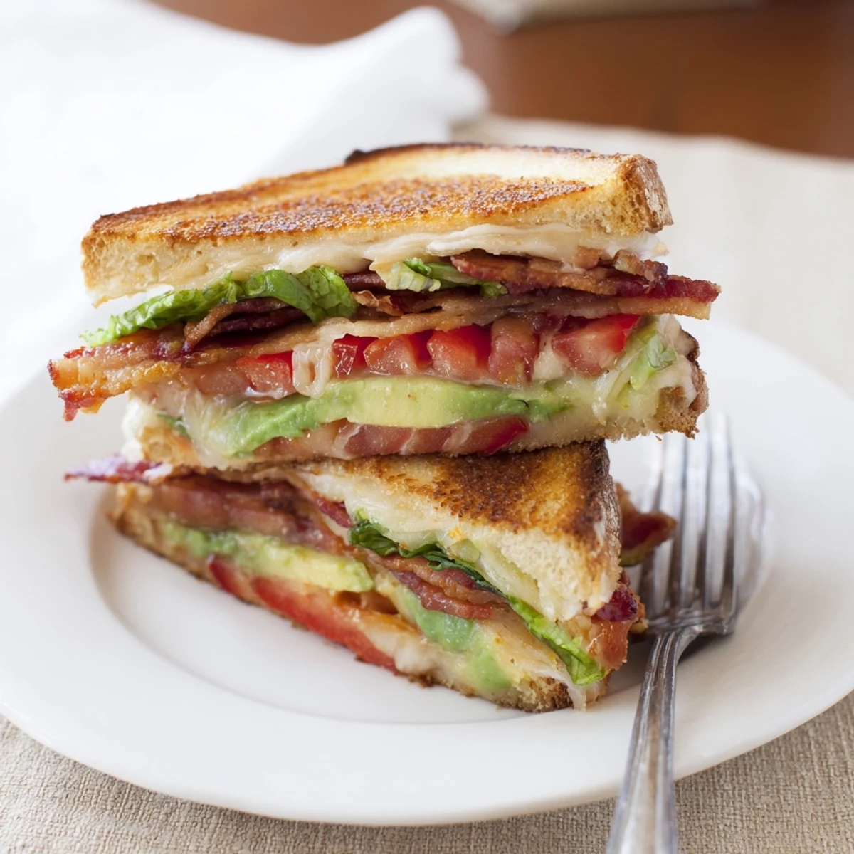 Golden grilled sourdough layers hold melted cheddar, crispy bacon, ripe avocado, fresh tomato, and crisp lettuce in this Avocado BLT Grilled Cheese.  