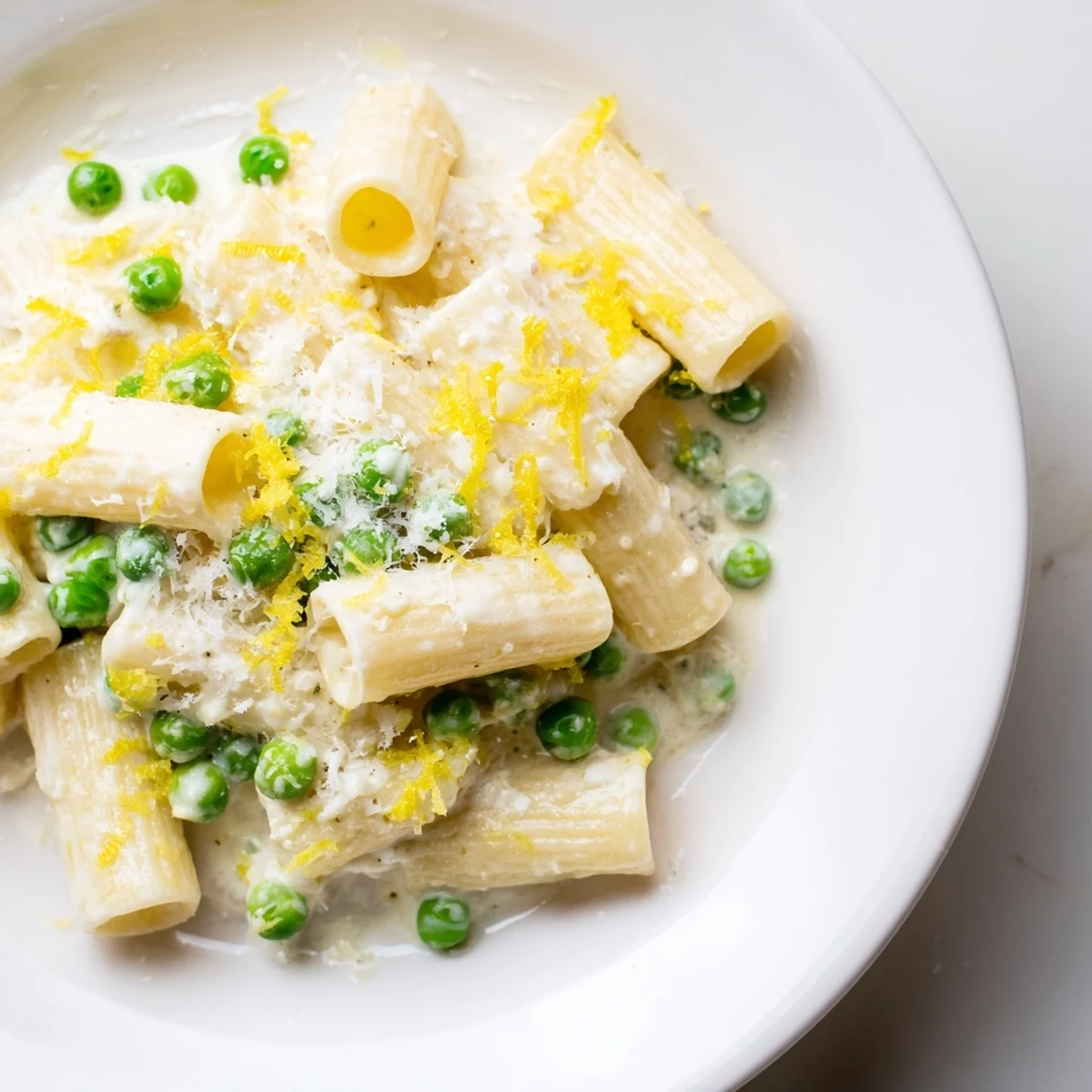 A bowl of vibrant Pea & Lemon Ricotta Pasta, garnished with fresh basil and extra Parmesan, shines in a sunlit kitchen.