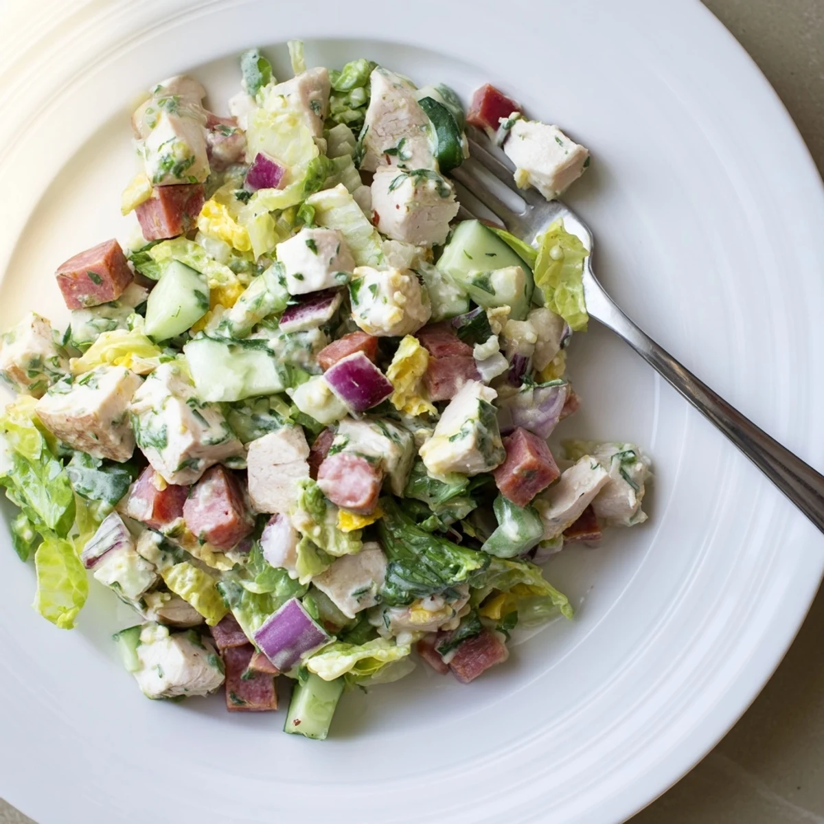 A close-up of Italian Deli Chopped Chicken Salad with juicy tomatoes, pepperoncini, and creamy provolone tossed in herb dressing.  