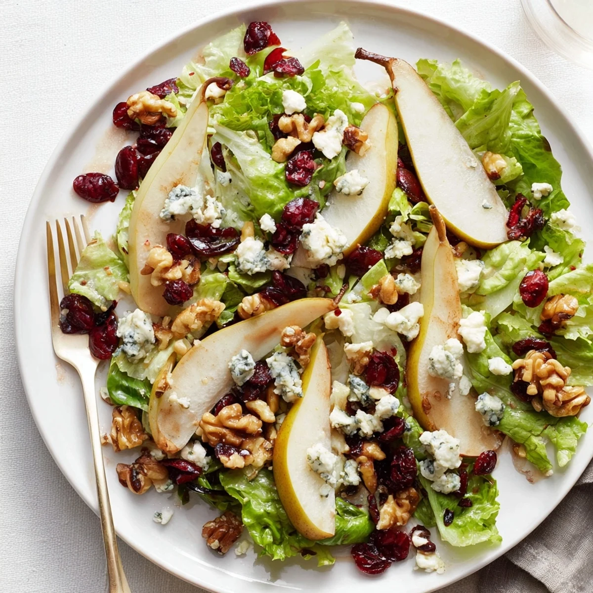 Bright salad recipe topped with sweet pears, tangy blue cheese, crunchy nuts, and a glistening honey-balsamic dressing for a refreshing side dish.