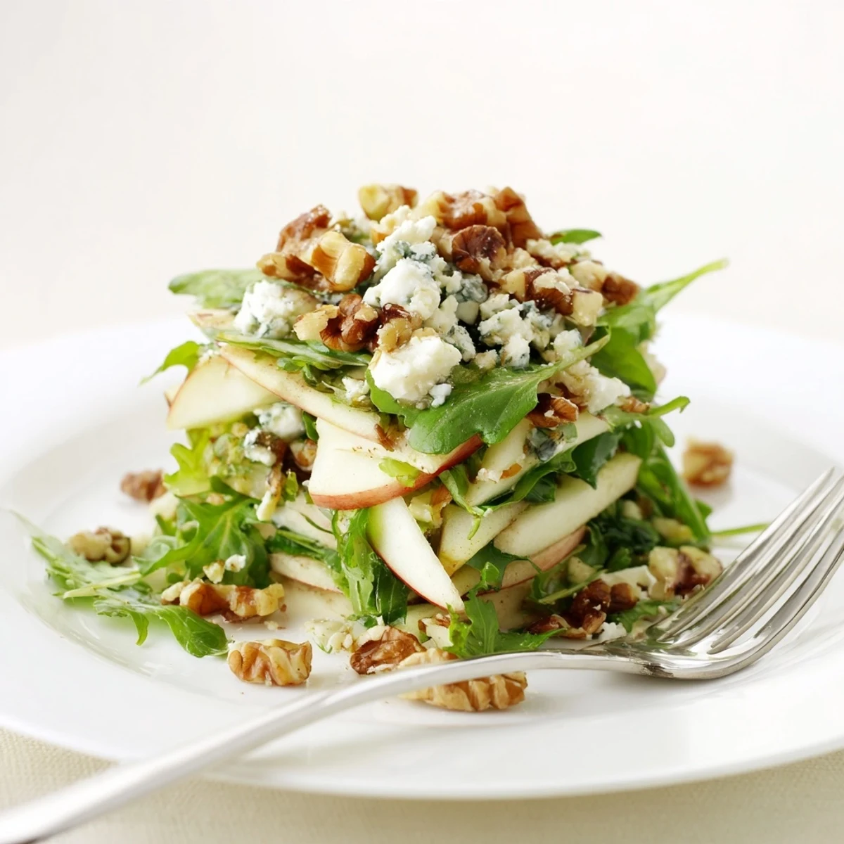 Apple and walnut salad served over arugula with a light honey-Dijon dressing, perfect for a quick vegetarian appetizer.