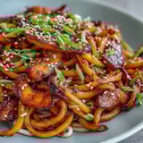 A vibrant bowl of Gochujang Swede Noodles featuring glossy noodles and fresh cilantro garnish.