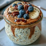 Golden High-Protein Peanut Butter Overnight Oats layered with fresh blueberries, ready to grab and go for breakfast.