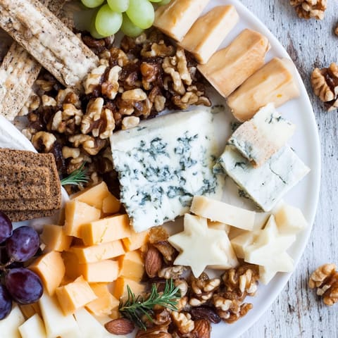 This Crescent Moon & Stars Cheese Board includes star-shaped gouda, creamy cheeses, and glistening dark grapes on display.