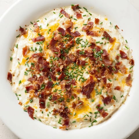 Close up shot of melty Cheesy Bacon Ranch Dip, showcasing savory bacon crumbles on top.