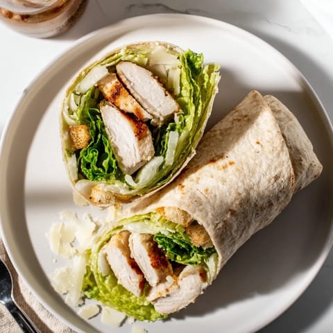 Freshly assembled Caesar Chicken Salad Wrap sliced in half to show the hearty filling, ready for a satisfying handheld lunch.  