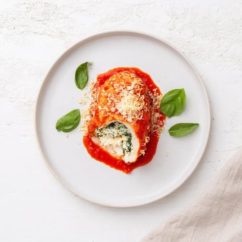 Overhead view of Spinach Ricotta Stuffed Chicken, showing creamy filling in a skillet with crushed tomatoes.