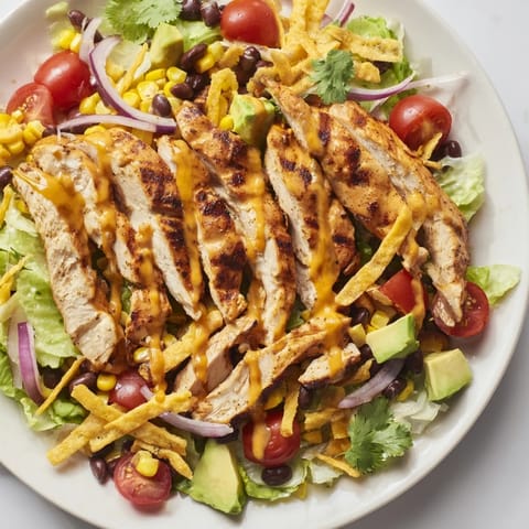 Freshly grilled honey lime chicken rests on a colorful salad with cherry tomatoes, red onion, and crunchy tortilla strips.