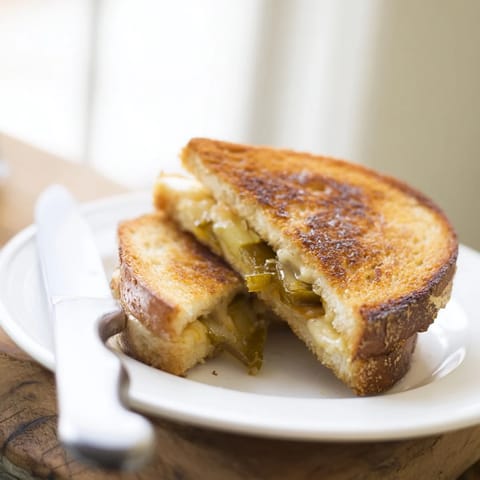 Sizzling Jalapeño Pepper Jack Grilled Cheese cooking in a buttered skillet, with bubbly edges and steam rising.