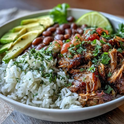 Golden-brown slow-cooked carnitas with fluffy rice and pinto beans in a bowl.