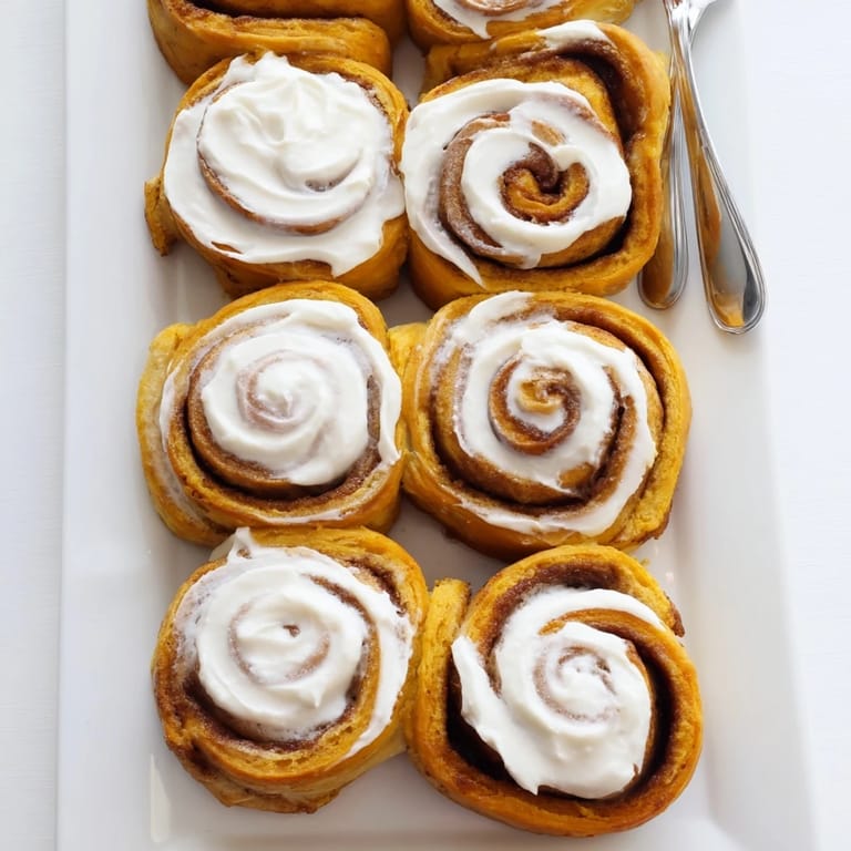 Warm Pumpkin Cinnamon Rolls with swirls of cinnamon sugar filling and rich cream cheese glaze.