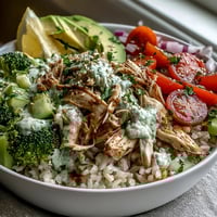 Freshly shredded rotisserie chicken, vibrant cherry tomatoes, and creamy avocado fill this wholesome Rotisserie Chicken Bowl over brown rice.